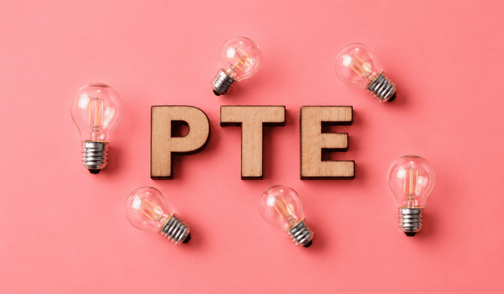 PTE Academic exam preparation with PTE study materials, notebook, pen and glasses