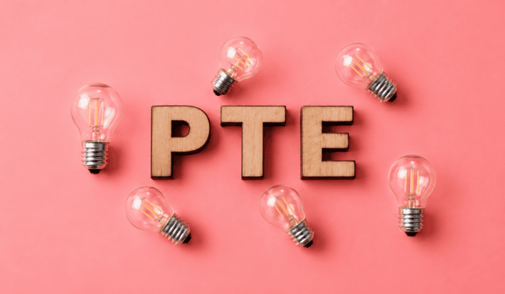 PTE Academic exam preparation with PTE study materials, notebook, pen and glasses